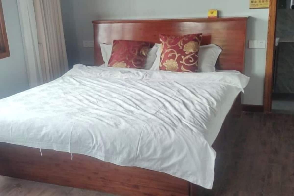 Un lit avec une tête de lit en bois, une literie blanche et des coussins à motifs.