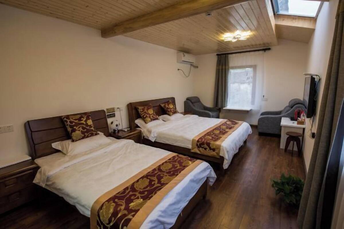 Une chambre d’hôtel avec deux lits, un bureau, une chaise et une fenêtre.