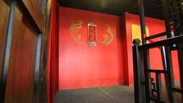 A room with a red wall, a wooden floor, and a black metal gate.