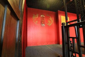 Una habitación con una pared roja, suelo de madera y una reja de metal negro.