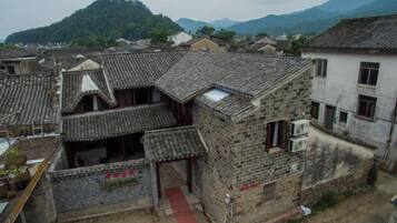 A traditional building with a tiled roof, a red pathway, and a mountainous backdrop.