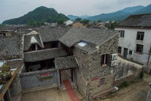Un edificio tradicional con techo de tejas, un sendero rojo y montañas al fondo.