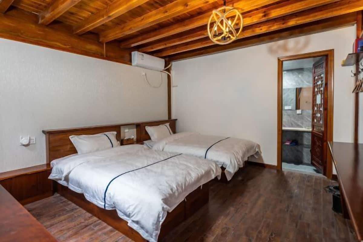 Une pièce avec un plafond en bois, un lit avec une literie blanche, une table de chevet en bois et un luminaire suspendu.