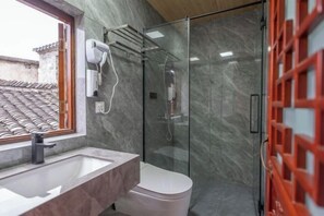 A bathroom with a glass shower enclosure, a white toilet, a sink with a marble countertop, and a hairdryer mounted on the wall. - Ninghai Shusong Hotel (Ninghai)