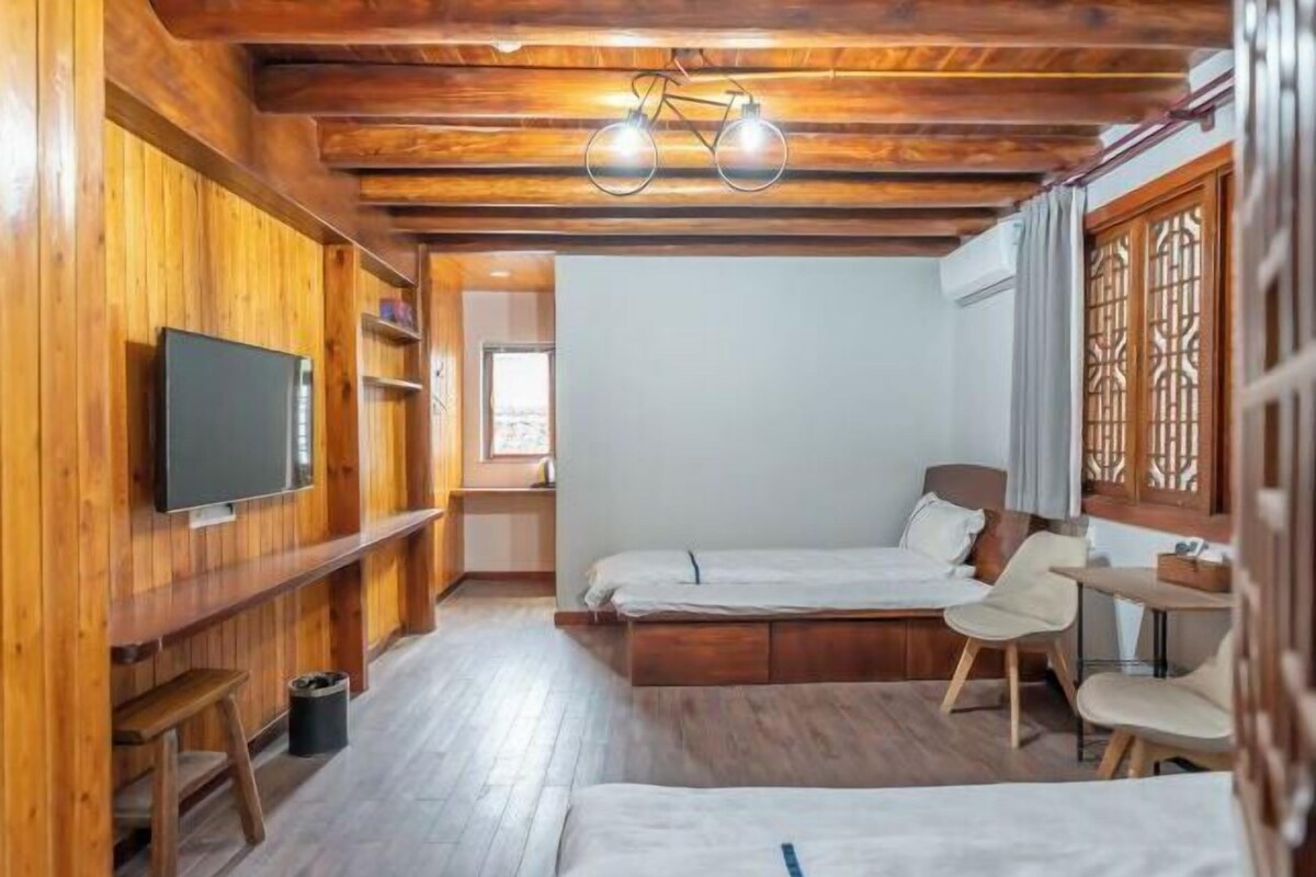 Una habitación con paneles de madera, una cama, un televisor, un escritorio y una silla.