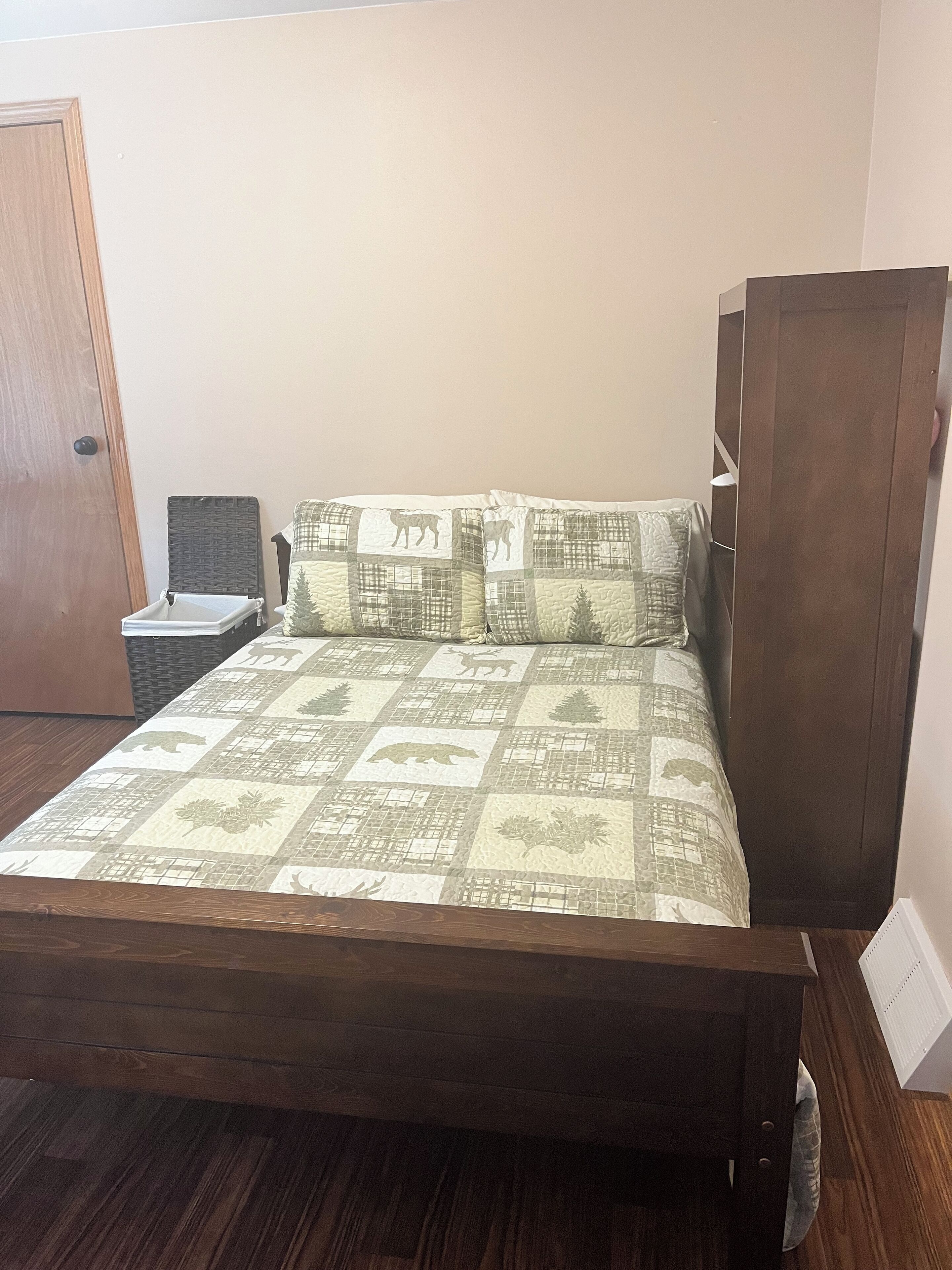 A bed with a quilted pattern, a wooden headboard, and a nightstand with a lamp.