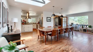 Une cuisine spacieuse avec un coin repas, un plancher en bois et de grandes fenêtres.