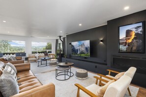 Una sala de estar moderna con un televisor de pantalla plana grande, asientos cómodos y una chimenea.