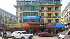 Un edificio de varios pisos con diversos comercios en la planta baja, incluyendo un hotel y varias tiendas.