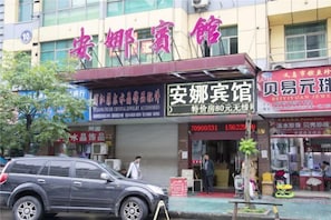 A storefront with signage for a jewelry store and a nearby car parked outside. - Anna Hostel (Yiwu)