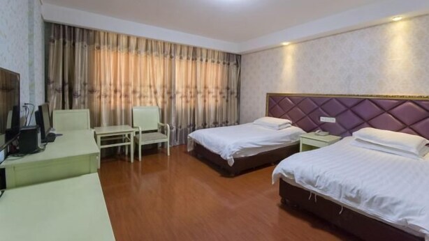 Una habitación de hotel con dos camas, un escritorio, una silla y un televisor.