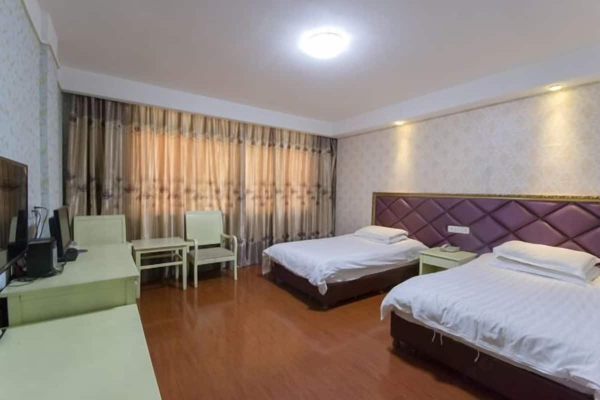A hotel room with two beds, a desk, a chair, and a television.
