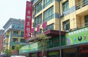 A multi-story building with commercial signage, including a prominent red banner and a green sign with white text. - Anna Hostel (Yiwu)