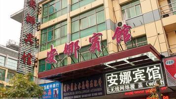 A building with a sign that reads '安娜宾馆' and another sign below it that says 'ecal room 80%.'