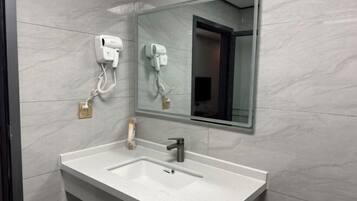 A bathroom with a white sink, a mirror, and two hair dryers mounted on the wall.