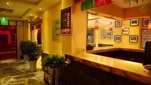 A reception area with a stone floor, a reception desk, potted plants, and framed pictures on the wall. - Holiday Weekend Hotel (Xiahe)