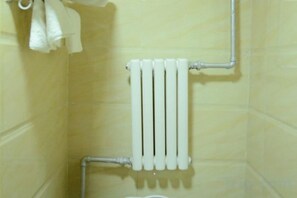 A bathroom with a white radiator, a towel rack, and a toilet. - Holiday Weekend Hotel (Xiahe)