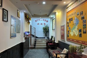 A hotel lobby with a reception desk, seating area, and a staircase leading to the upper floors. - Holiday Weekend Hotel (Xiahe)