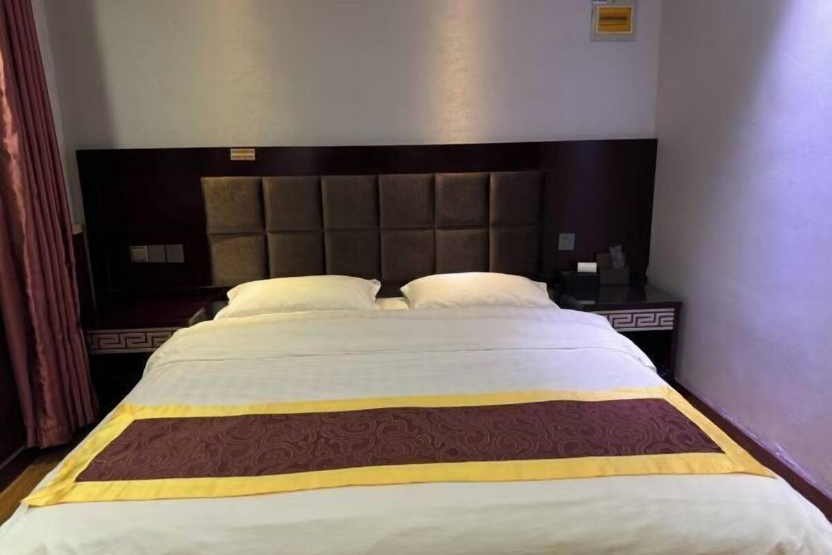 A hotel room with a large bed, a headboard, and a bedside table.