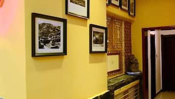 A hallway with framed photographs on the wall, a marble counter, and a door.