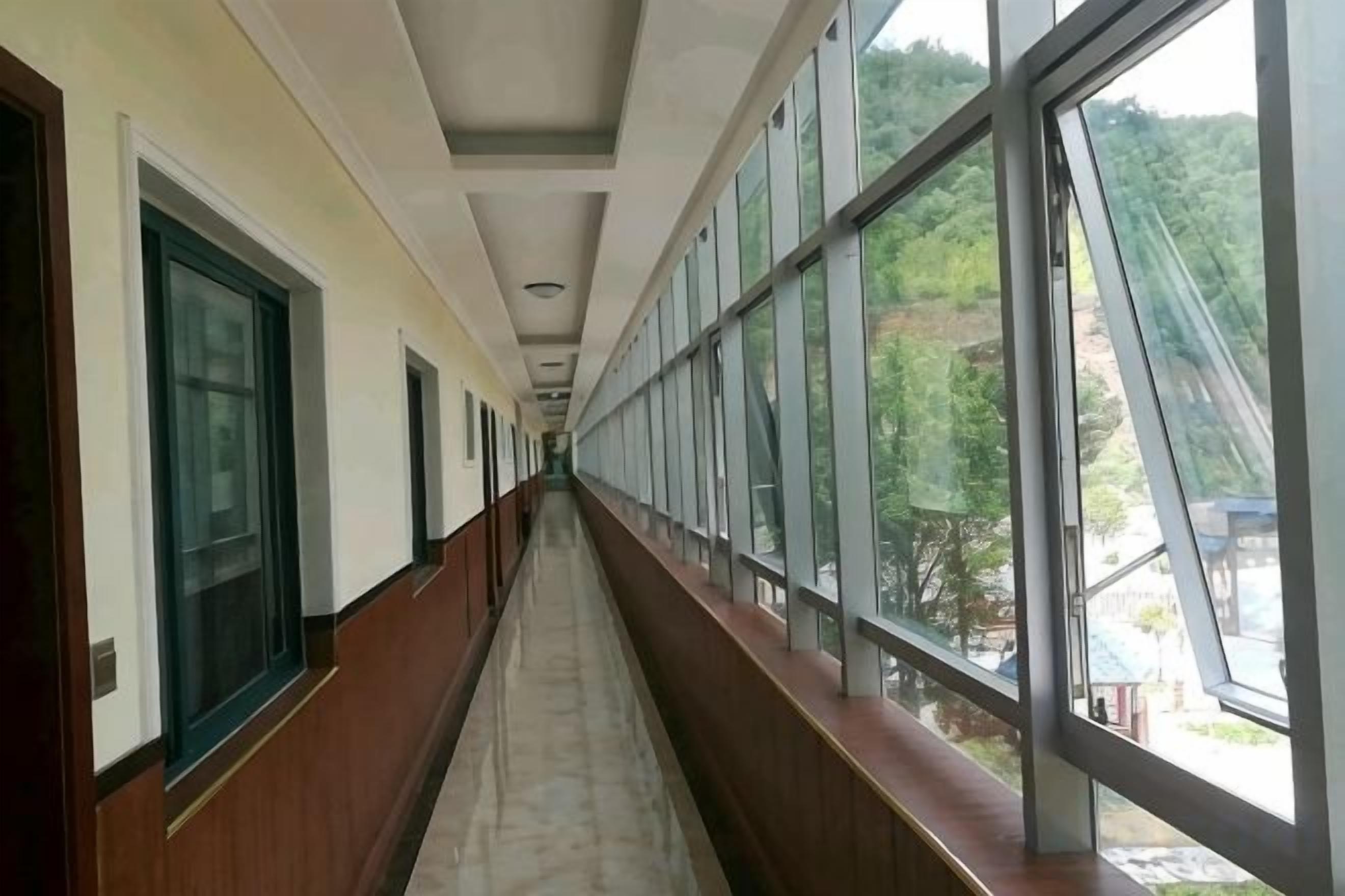 A corridor with large windows and doors on both sides.