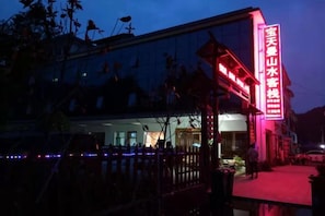A building with a prominent sign, a gated entrance, and a paved walkway. - Baotianman Shanshui Inn (Neixiang)
