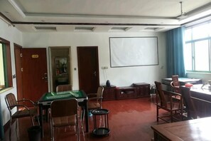 A conference room with a pool table, chairs, a projector screen, and a large window.