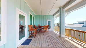 A covered porch with wooden furniture and a view of the beach. - Private Pool and Golf Cart Included (Port Aransas)