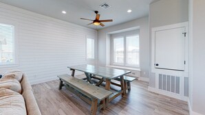 A spacious room with a wooden table and benches, white walls, and a ceiling fan. - Private Pool and Golf Cart Included (Port Aransas)