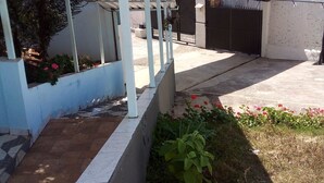 A covered outdoor area with a tiled floor, a metal roof, and a gated entrance. - Hotel pousada chic (Tatui)