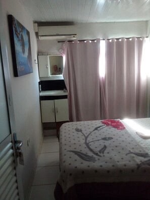 Un dormitorio con cama, escritorio con espejo, aire acondicionado y baño con inodoro.