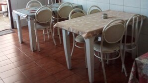 A dining area with a table and chairs, a painting on the wall, and tiled flooring. - Hotel pousada chic (Tatui)