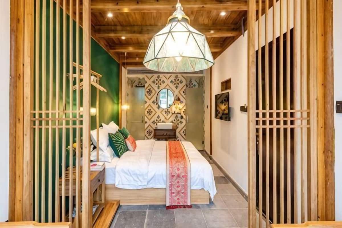 Une pièce de style japonais traditionnel, avec un lit, des portes coulissantes en bois, un luminaire suspendu et un mur orné de motifs.