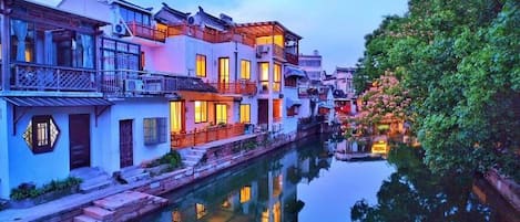 Um edifício tradicional à beira do canal, com vários níveis, um canal refletor e um jardim bem cuidado.