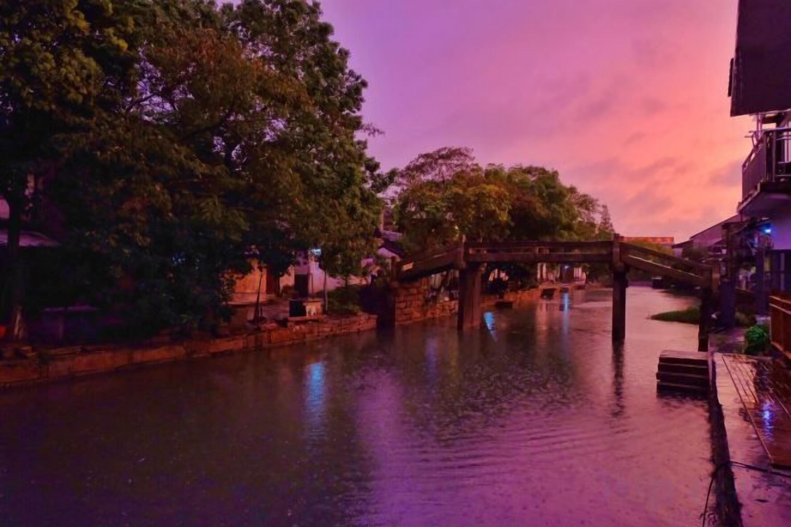 Un río con un puente de madera, árboles y edificios a lo largo de las orillas.