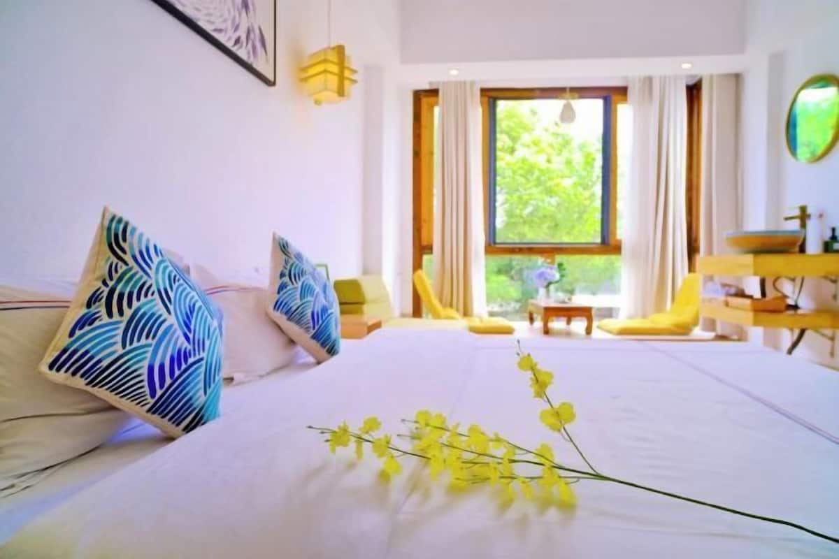 Une chambre d’hôtel avec un lit, une fenêtre avec des rideaux, une petite table et une chaise.