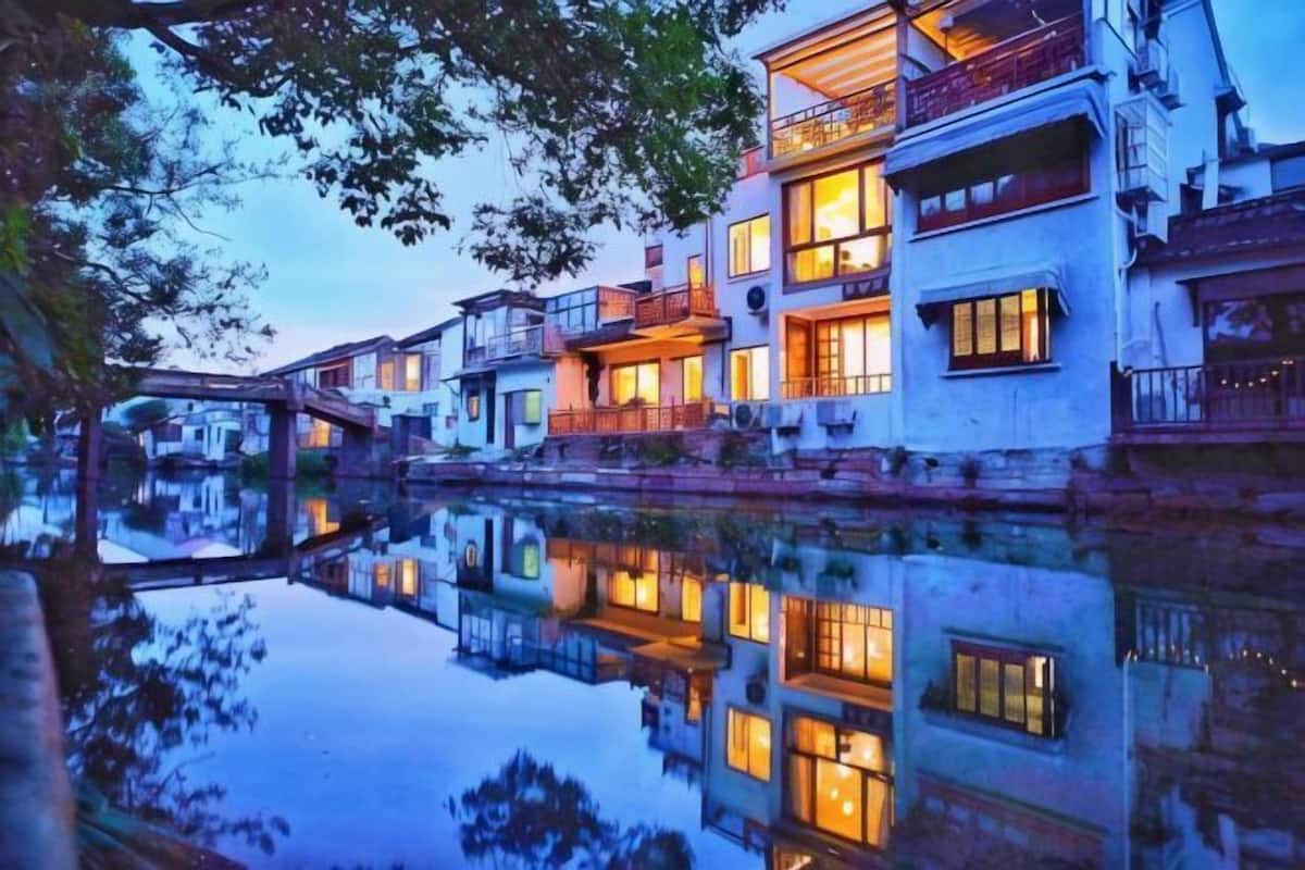 Un bâtiment de style traditionnel, doté de nombreux balcons, dont le reflet se mire dans l’eau.