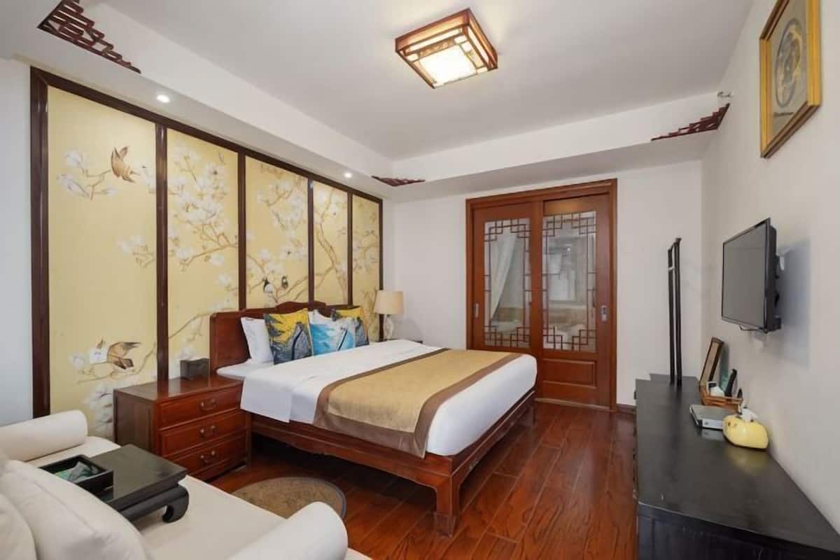 Une chambre à coucher comprenant un lit, une table de chevet, une lampe, un téléviseur et un paravent décoratif.