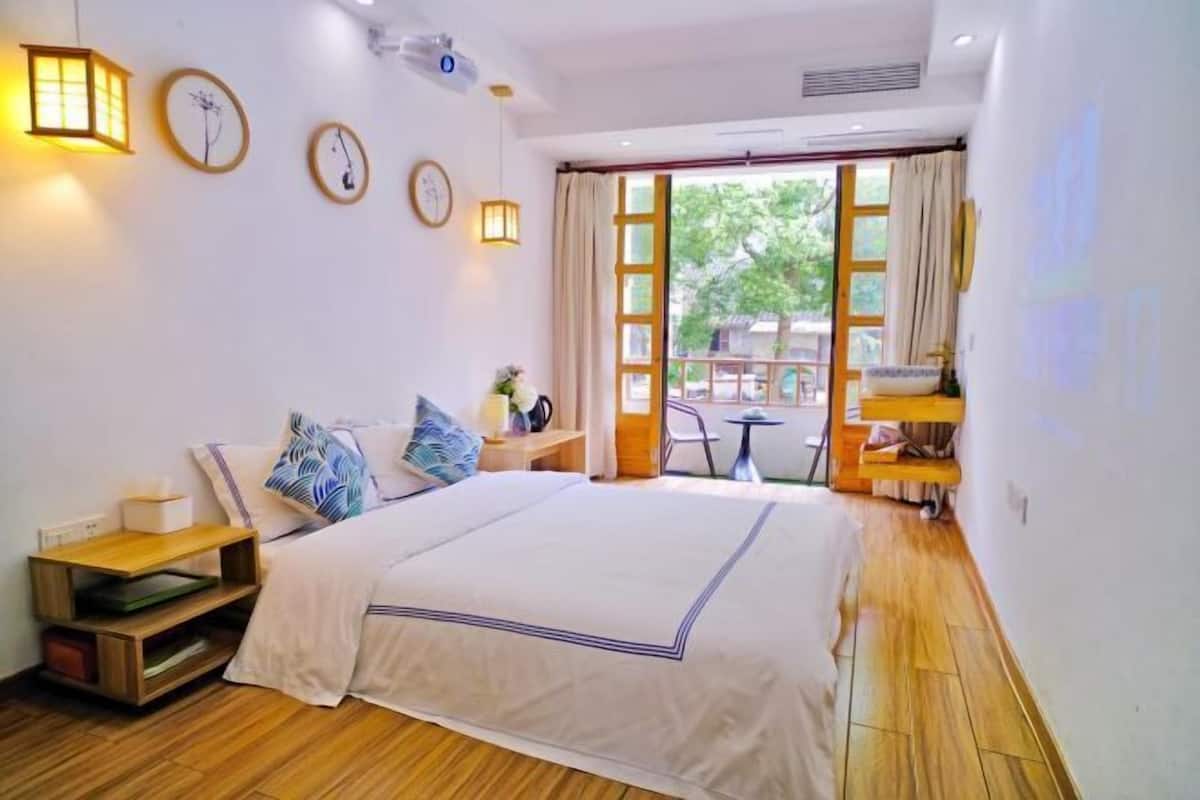 Une chambre à coucher avec un lit, des tables de chevet, une fenêtre avec des rideaux et une vue sur l’extérieur.