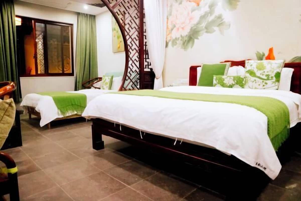 Une chambre d’hôtel avec deux lits, une grande fenêtre avec des rideaux, un mur décoratif et une chaise en bois de style traditionnel.