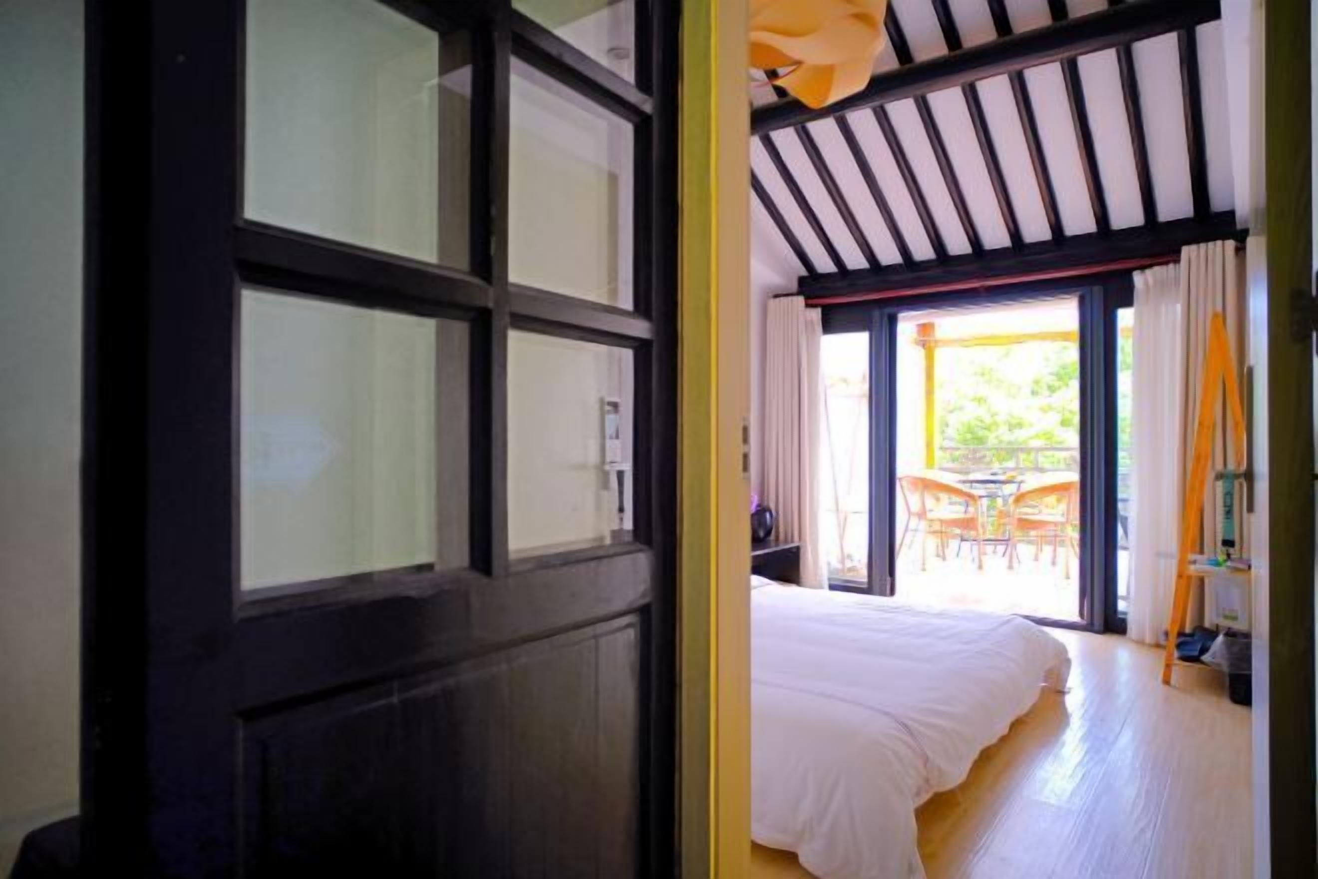 A bedroom with a large bed, a sliding glass door leading to an outdoor patio with chairs.