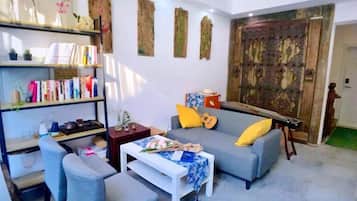 Una sala de estar con sofá, sillones, una mesa de centro y una estantería.