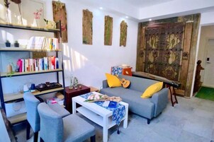 Una sala de estar con sofá, sillones, una mesa de centro y una estantería.