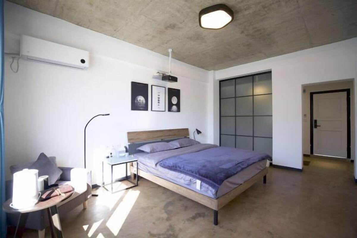 A modern bedroom with a bed, bedside table, and a desk with a chair.