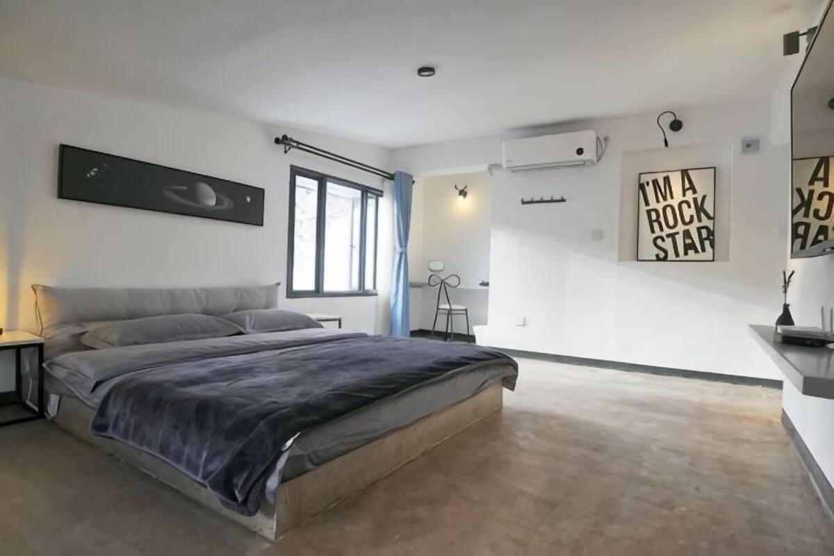 A modern bedroom with a bed, bedside tables, a window, and wall art.