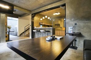 A modern kitchen with bar stools, a dining table, and pendant lighting.