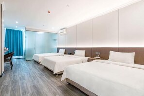 A hotel room with three beds, a desk, and a blue curtain. - Impression Hotel (Zhuhai)