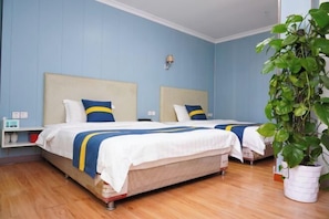 Een hotelkamer met twee bedden, een potplant en een plank met toiletartikelen.