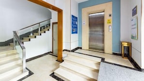 A hotel lobby with a staircase, an elevator, and a reception desk. - Impression Hotel (Zhuhai)