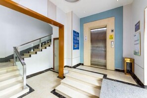 Un hall d’hôtel avec un escalier, un ascenseur et un comptoir d’accueil.